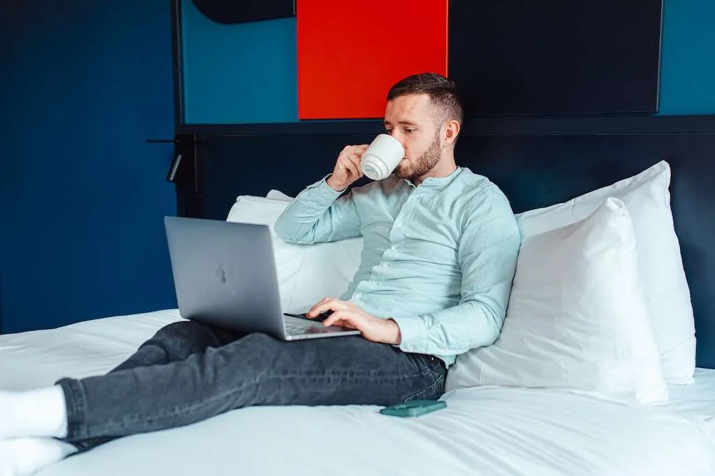 Guest relaxing on a Kabannas bed with a laptop and coffee
