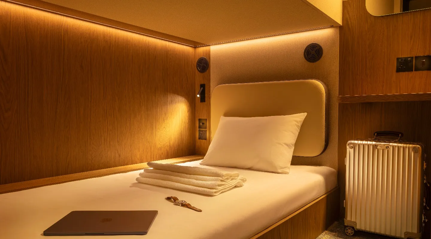 A cosy Kabannas single bed lower Cabin in warm lighting with space for luggage and belongings  