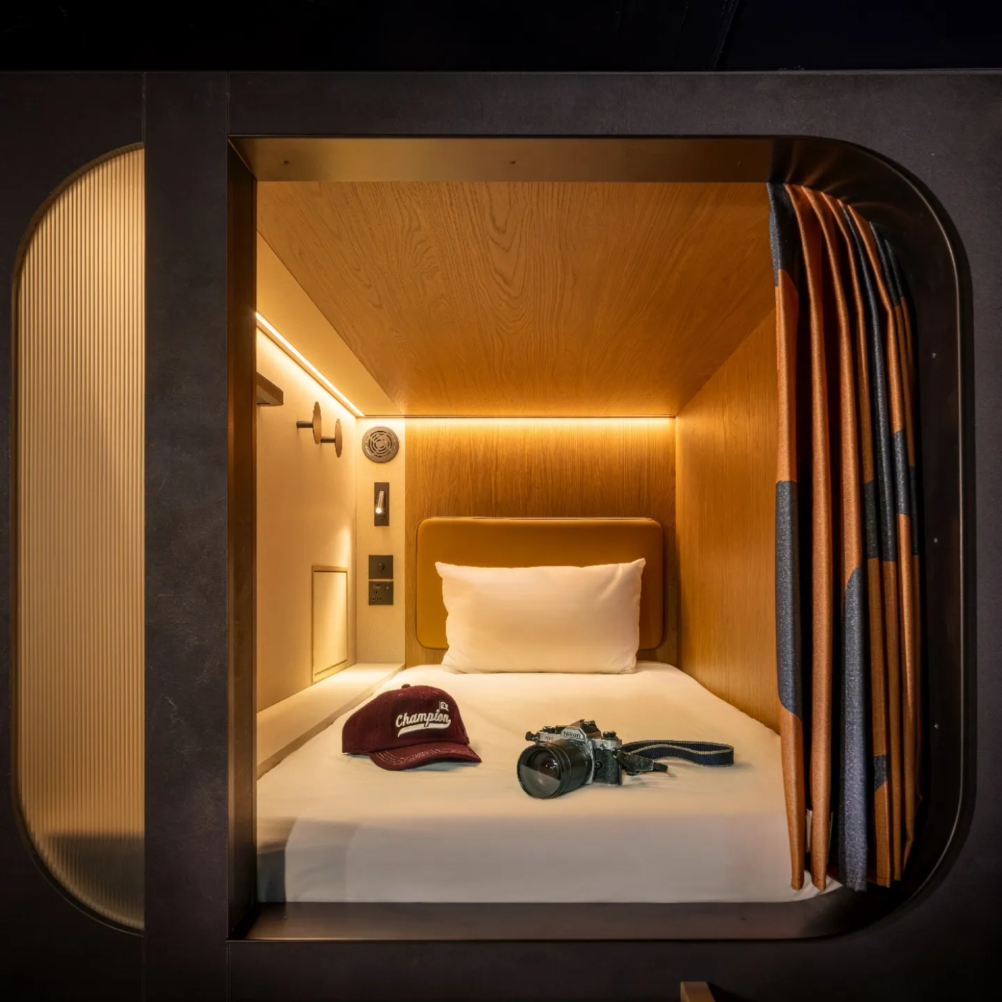 A cosy Kabannas Pod showing a warmly lit interior with clean white sheets and wood paneling 