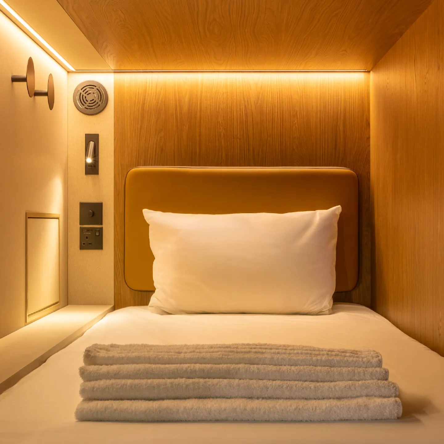A cosy Kabannas Pod showing a warmly lit interior with clean white sheets and wood paneling 