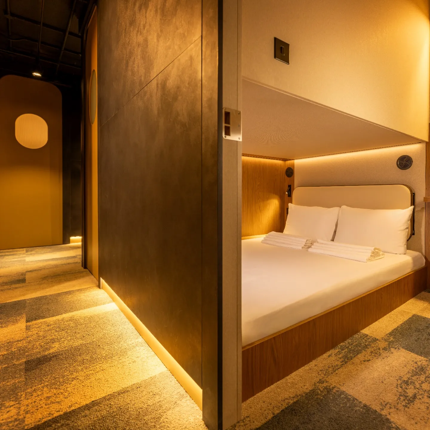 A Kabannas Cabin room with warm lighting, clean white sheets and wood paneling 
