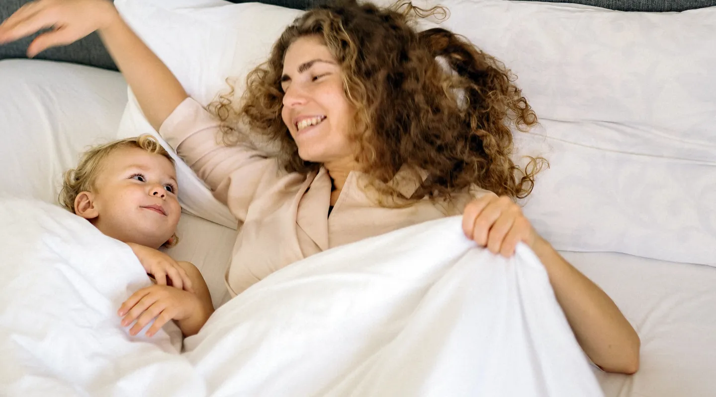 A mother and child tucked up in a comfortable bed in a Kabannas Nest room